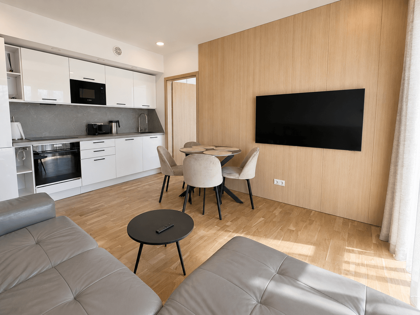 Jauki svetainės ir virtuvės zona moderniuose apartamentuose