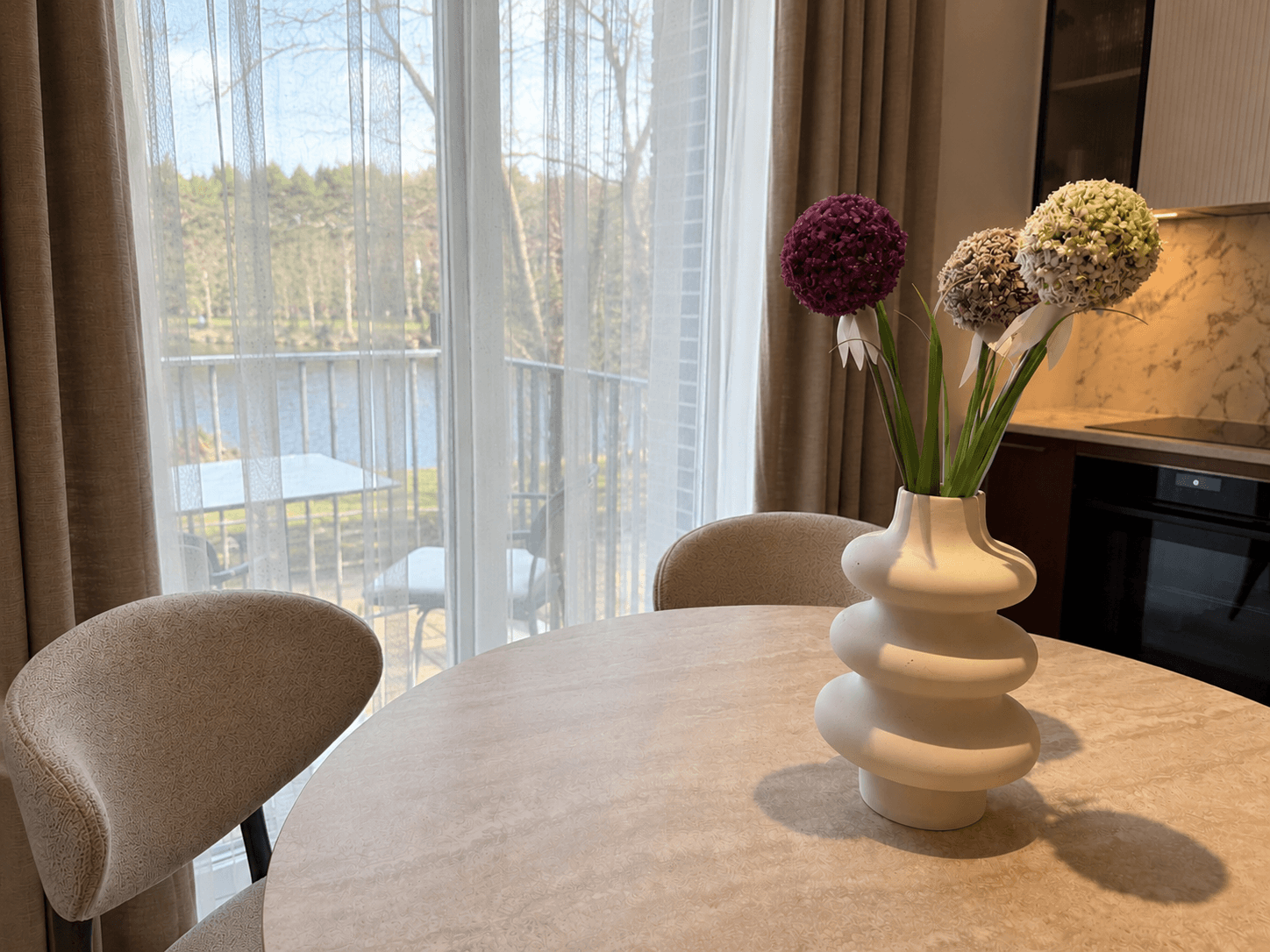 Jauki virtuvės zona moderniuose apartamentuose su vaizdu pro langą į vandens telkinį